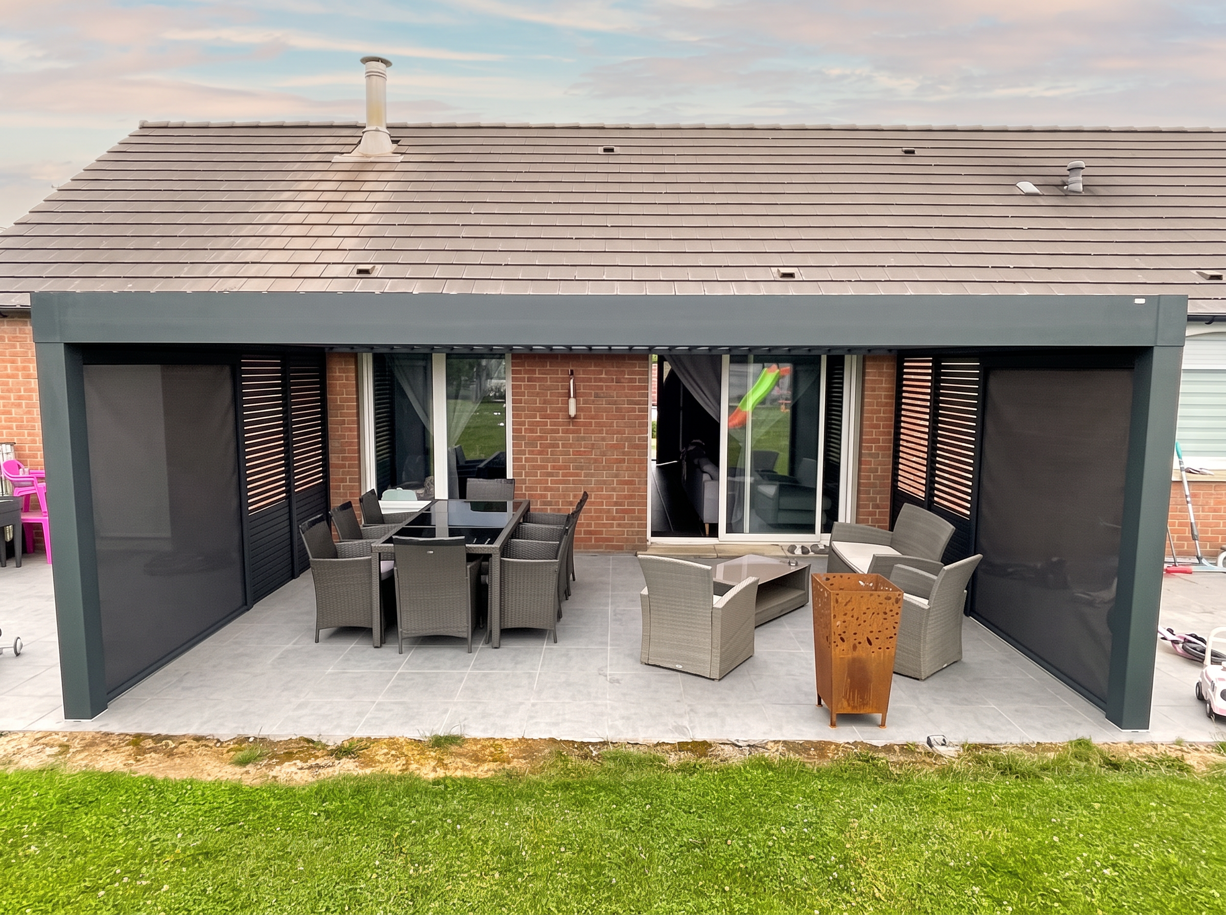 Pergola bioclimatique anthracite avec stores, installée par VITREC sur une terrasse